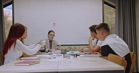 Students and professor study together during class. They collaborate on a project, discuss ideas, and learn from each other in a friendly classroom environment.