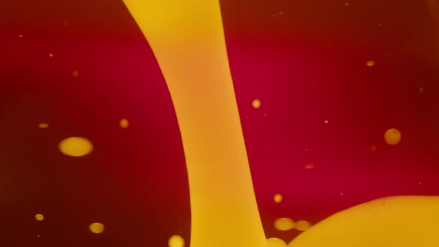 Abstract yellow lava bubbles floating in liquid on red background. Slow motion. 