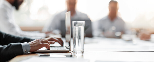 Business Meeting Concept. Unrecognizable Businessman Sitting On Corporate Meeting In Office, Focus On Laptop And Glass Of Water. Cropped