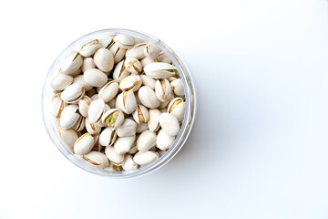 A clear plastic container filled with pistachio nuts in their partially open shells, showcasing the vibrant green nuts inside. Perfect for food photography, highlighting textures and contrasts