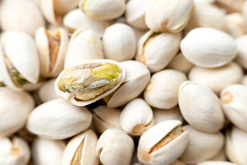 A detailed close-up view of several pistachio nuts in their shells, with some shells partially open, showcasing the nut inside. The intricate textures and natural appearance of the pistachios are high