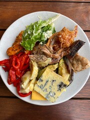 Buffet BBQ lunch combination of meat, vegetables and cheese on the white plate