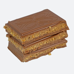 Milk chocolate pieces filled with cookie dough caramel butter nuts filling stacked isolated on white background