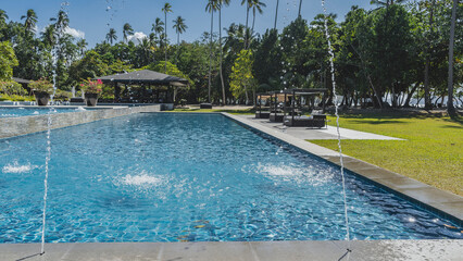 Outdoor swimming pool. Water jets around the perimeter. Ripples on the water, splashes. Sun beds...