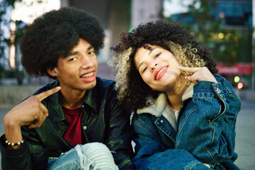 Couple of Latino friends with braces and afro hair enjoying a day at dusk, holding hands on a date, sharing. Lots of joy, laughter and friendship.