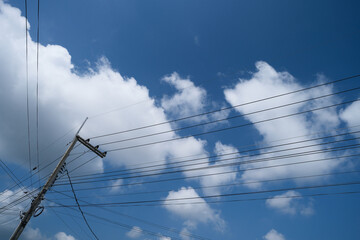 Electrical pole against blue sky and direction of electrical wires