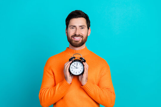 Photo of cheerful attractive man wear stylish clothes hold alarm clock isolated on aquamarine color background