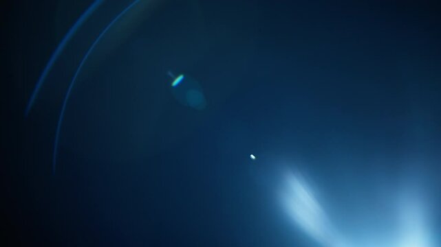 Blue lens flares overlay fading out into black background. Slow motion.