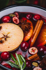 Cranberry non-alcoholic mulled wine in a ladle, with cranberries, cinnamon, apples and citrus fruits with spices