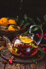 Tea with berries, citrus fruits and spices in a glass teapot