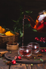 Tea with berries, citrus fruits and spices in a glass teapot and mugs