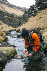Hydrologist measuring water levels in a remote river with handheld instruments, rugged terrain