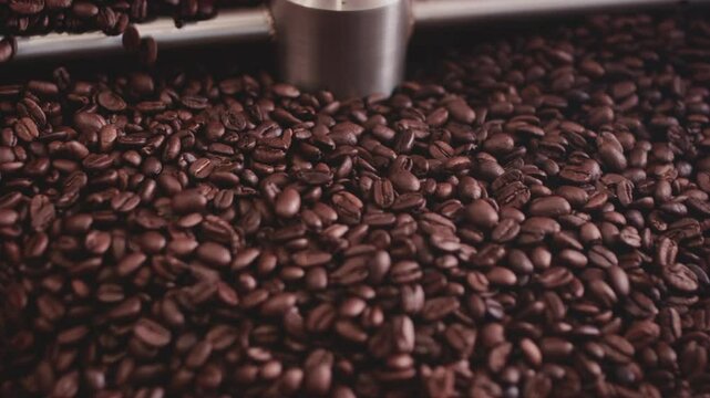 Macro close up: Coffee seeds or beans in a roasting machine, mixing aroma beans. Preparation fresh aroma caffeine on manufacturing warehouse. Production of fresh fried coffee