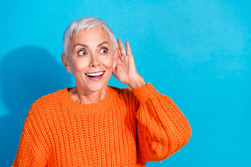 Photo of amazed old lady hold hand ears look empty space hear rumors wear orange jumper isolated...