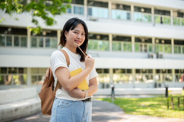 A pretty Asian female college student standing on her college campus, smiling at the camera.