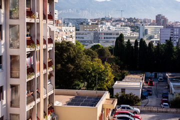 Close view of residential apartments with solar panels on a rooftop, surrounded by dense greenery,...