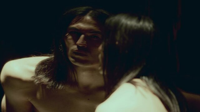 Handsome male dancer with shirtless torso moving in dark studio with distorting mirror, that warping his reflection in surreal way