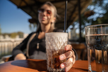 Blonde woman drinking ice coffee in a cafe outdoor