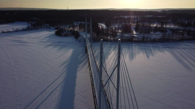 Aerial view of a cable-stayed bridge over a frozen lake during a beautiful winter sunset in nothern Sweden