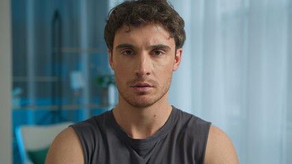 Serious Caucasian man turn head looking at camera confident sportsman sporty male home athlete expression training strong muscular power active lifestyle handsome guy face workout healthy bodybuilder