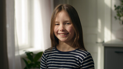Happy Caucasian European little girl looking at camera smiling schoolgirl pupil daughter offspring...