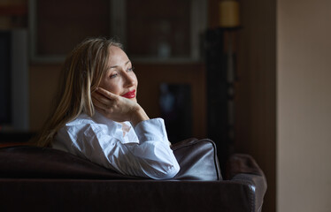 Pensive blond woman relaxing in armchair at her office