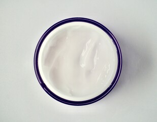 White moisturizer skin care cream inside round jar container object photography isolated on horizontal white background from above view angle.