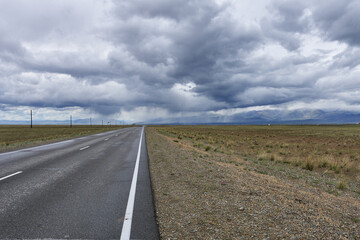 Road in the steppes of Mongolia under a cloudy sky.