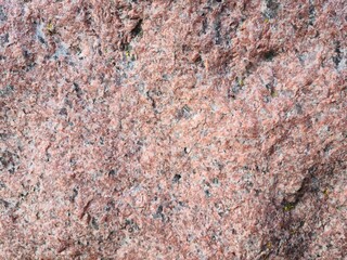 Textured surface of pink granite showing mineral details in natural light