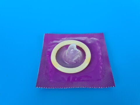 A close-up view of a condom on a blue background highlighting its packaging and design for safe sex awareness