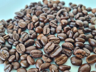 Freshly roasted coffee beans spread out on a light background, highlighting different shades and textures