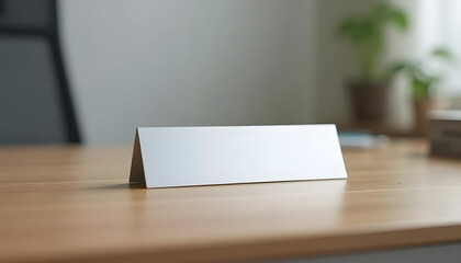 Blank tabletop nameplate on wooden desk in modern office with greenery in background