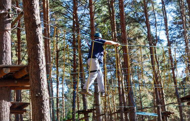 A man is walking across a rope bridge in a forest