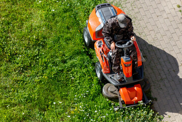 A person operating a lawn mower in a park, cutting the grass.