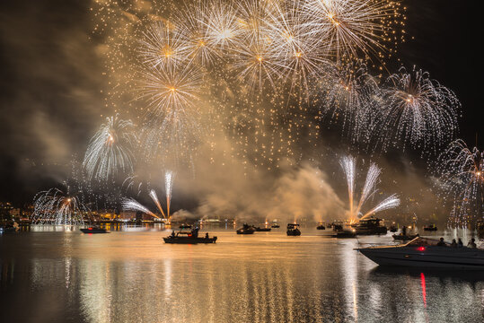 Fireworks at night over lake with boats. Ponte Tresa and lake Lugano with a fireworks display, northern Italy. Tourism and leisure concept