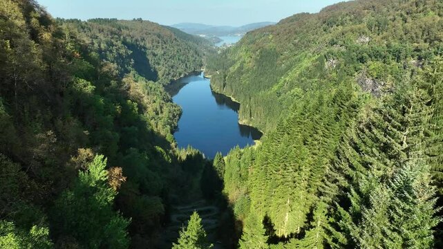 Reverse aerial over Kossdalen lake with Osteroy landscape and Osterfjorden in the background