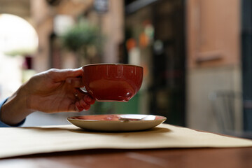 Woman hand holding beautiful ceramic cup with coffee or tea