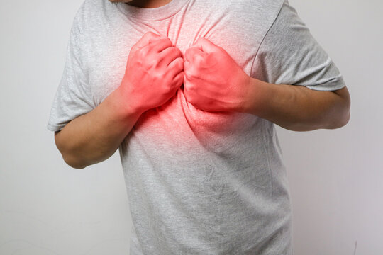 A man feeling exhausted and suffering from heart pain and injury on isolated white background with red spot. Health care and medical concept.