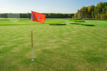 Obraz premium A Beautiful and Serene Scene Depicting a Tranquil Golf Course with a Bright Flag at Its Peak