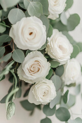 Obraz premium Elegant white roses surrounded by lush green eucalyptus leaves create serene and romantic atmosphere, perfect for weddings or special occasions