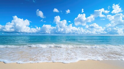 Fototapeta premium Sandy beach with ocean waves beneath a backdrop of blue sky and fluffy clouds