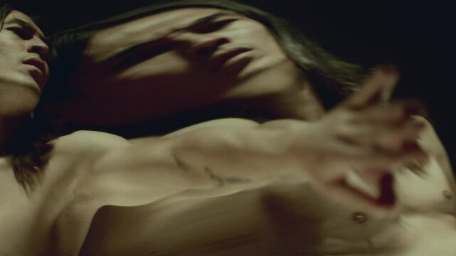 Shirtless male dancer moving with hypnotic grace against distorting mirror, surreally reshaping his reflection in captivating performance