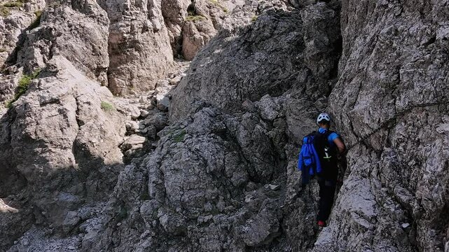 Man climbs rocky mountain walls, dangerous passages with chains, summer, Grignetta, and Italian Alps. Aerial lateral drone