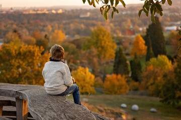 Amazing blond boy, cute child, enjoying a sunny day in Botanical garden in Prague during the halloween exhibition of pumpkins