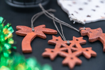 Vintage ceramic terracotta Christmas tree decorations lie on dark table next to cotton bag with stars and tinsel. Side view