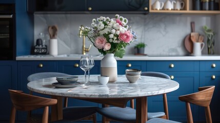Marble dining table in Scandinavian kitchen with modern monochrome decor and blue drawers on wooden furniture, adorned with tableware and flower vases.