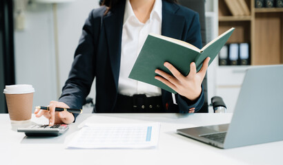 Business woman using tablet and laptop for doing math finance on an office desk,
