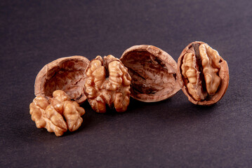 Four whole walnuts in the shell laid out in a row on a black background