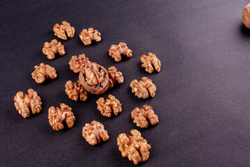 Four whole walnuts in the shell laid out in a row on a black background
