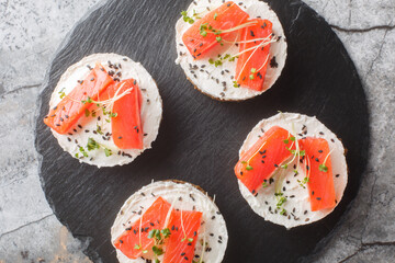Healthy breakfast, salmon rye bread sandwich with cream cheese, sesame and micro greens close-up on...
